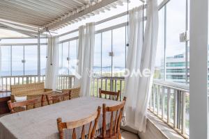 a dining room with a table and chairs and large windows at Apartamento a 300m da Praia do Forte em Cabo Frio in Cabo Frio