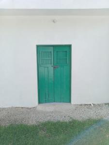 a green door on the side of a white building at El rinconcito in Mérida