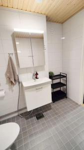a white bathroom with a sink and a mirror at Lovely new studio for 3 - close to airport, free parking in Vantaa