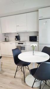 una cocina con mesa blanca, sillas y una mesa con flores en Lovely new studio for 3 - close to airport, free parking, en Vantaa