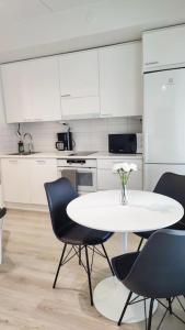 eine Küche mit einem weißen Tisch und Stühlen und einem Tisch mit Blumen in der Unterkunft Lovely peaceful studio - close to airport, free parking in Vantaa + 4 Fotos