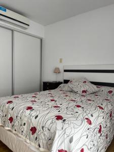 um quarto com uma cama com flores vermelhas em Alameda Departamento Temporario em Santa Fé