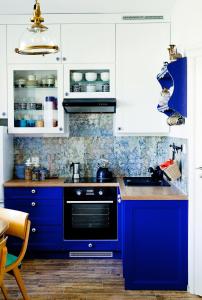 a blue kitchen with white cabinets and a sink at Przystanek w kolorach świata in Jelenia Góra