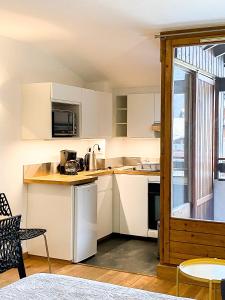 eine kleine Küche mit weißen Schränken und einem Fenster in der Unterkunft 3- Charmant studio Brides-les-Bains in Brides-les-Bains