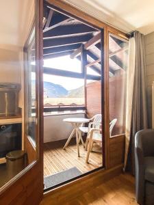 Zimmer mit einem Balkon mit einem Tisch und einem Fenster in der Unterkunft 3- Charmant studio Brides-les-Bains in Brides-les-Bains
