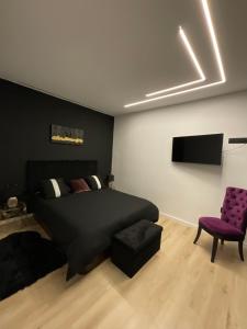 una camera con un letto nero e una sedia viola di VILLA HERMES a San Antonio de Benagéber