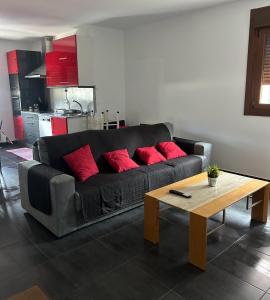 ein Wohnzimmer mit einem schwarzen Sofa und roten Kissen in der Unterkunft Bajo casa en Moaña in Moaña
