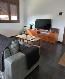 ein Wohnzimmer mit einem Sofa und einem TV in der Unterkunft Bajo casa en Moaña in Moaña