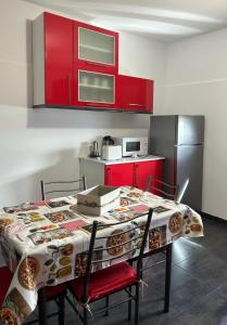 eine Küche mit einem Tisch mit Stühlen und roten Schränken in der Unterkunft Bajo casa en Moaña in Moaña