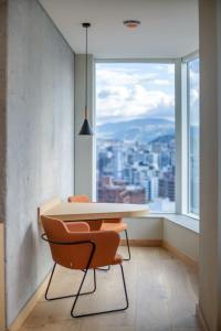 GO Quito Hotel في كيتو: غرفة طعام مع طاولة وكراسي أمام النافذة