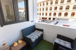 瓦倫西亞的住宿－DormForYou Plaza de Toros，阳台配有两把椅子和一张桌子,公寓大楼