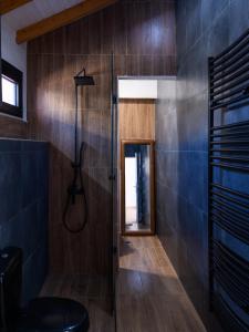 baño con ducha, paredes de madera y suelo de madera. en Owl's Nest, en Volos