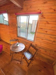 una habitación con una mesa y una silla en una cabaña en Lilafken Apart Pichilemu, en Pichilemu