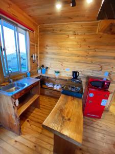Cabaña de madera con cocina con fogones y fregadero. en Lilafken Apart Pichilemu, en Pichilemu