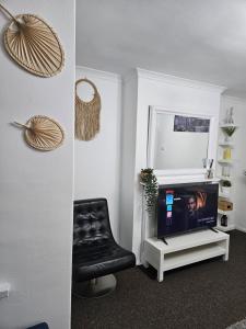 een woonkamer met een tv en een zwarte stoel bij Nariken Apartments, Cardiff in Cardiff