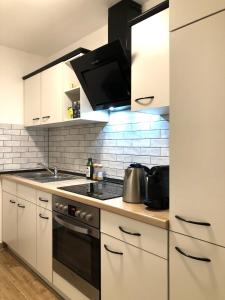 La cuisine est équipée de placards blancs et d'un four avec plaques de cuisson. dans l'établissement Appartement Hauptbahnhof, à Nuremberg