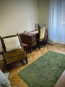 un salon avec une chaise, un bureau et un tapis dans l'établissement Tabán Apartman, à Pécs