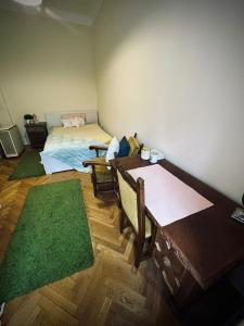 - une chambre avec un lit, une table et un tapis vert dans l'établissement Tabán Apartman, à Pécs