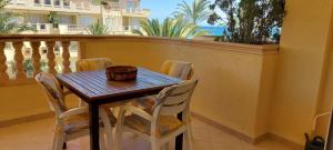 einen Holztisch und Stühle auf dem Balkon in der Unterkunft Estupendo apartamento en primera línea de playa y con vistas al mar in Denia