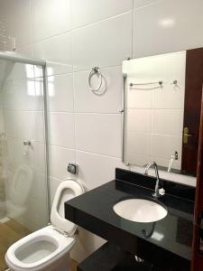 uma casa de banho com um WC, um lavatório e um espelho. em Sitio Aconchego de São Thomé em São Tomé das Letras