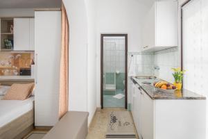 eine weiße Küche mit einem Waschbecken und einer Dusche in der Unterkunft Apartments Katana in Poreč