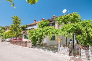 ein weißes Haus mit Bäumen vor einer Straße in der Unterkunft Apartments Katana in Poreč