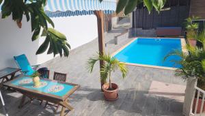 un patio con una mesa y una piscina en La PAPAYERAIE, en Le Marin