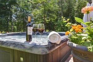 a bottle of wine and wine glasses on a hot tub at Front RIVER private BEACH 2 HOT TUBS 15 p SAUNA in Labelle