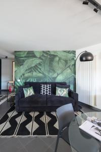un salon avec un canapé noir et une fresque murale. dans l'établissement Loft 36 by Omen Hospitality, à Rome