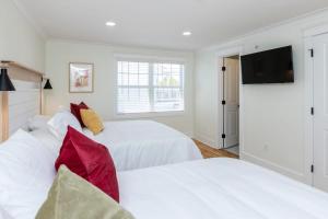 two white beds in a room with a flat screen tv at Cape Henry House Inn at Old Beach in Virginia Beach