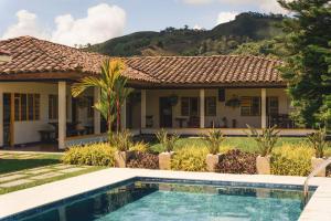 a villa with a swimming pool in front of a house at The Coffee Club Campestre in Chinchiná