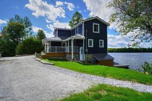 a black house on the shore of a lake at Waterfront Cottage w Sauna on Sharbot Lake in Sharbot Lake