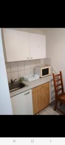 a kitchen with a microwave and a sink and a chair at Badacsonyi családi privát házak in Badacsonytomaj