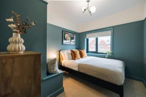 Schlafzimmer mit blauen Wänden und einem Bett mit orangefarbenen Kissen in der Unterkunft Regent's Retreat - Stunning home in Middlesbrough in Middlesbrough