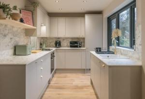 a large kitchen with white cabinets and a sink at Regent's Retreat - Stunning home in Middlesbrough in Middlesbrough