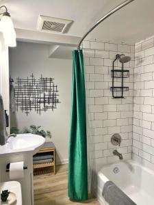 a bathroom with a green shower curtain next to a sink at *NEW* The Cozy Haven, 5 minutes to ATL airport in Atlanta