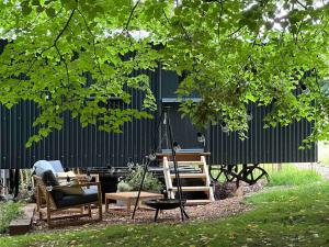 een tuin met stoelen en een schommel onder een boom bij Cornwall Woodland Dog Friendly Shepherd's Hut in Bodmin