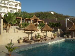 einen Pool mit Stühlen und Sonnenschirmen neben einem Gebäude in der Unterkunft La Villa d'O in Toubab Dialao