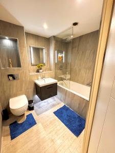a bathroom with a toilet and a sink and a tub at Bright & Spacious-Secured flat near slough station in Slough