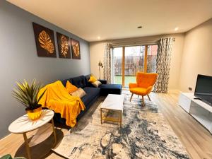 a living room with a blue couch and an orange chair at Bright & Spacious-Secured flat near slough station in Slough
