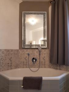 La salle de bains est pourvue d'une baignoire avec un miroir. dans l'établissement Ehemalige Klosterschmiede -Wirtschaftswunder-, à Ochsenhausen