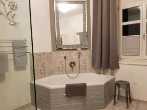 a bath tub in a bathroom with a mirror at Ehemalige Klosterschmiede -Wirtschaftswunder- in Ochsenhausen