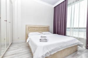 um quarto branco com uma cama grande e cortinas roxas em Raisson Ahotel D145 em Astana
