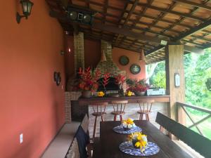 a porch with a table and chairs and a fireplace at Sitio Maravilha in Mulungu