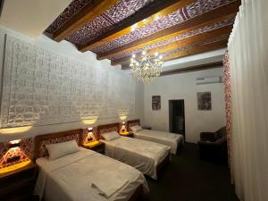 a hotel room with three beds and a chandelier at Dolon B&B Hotel in Bukhara