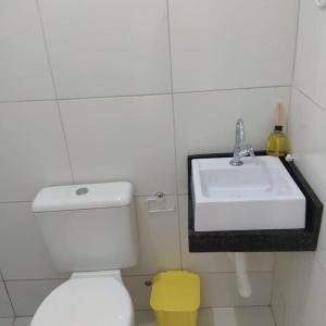 a bathroom with a white sink and a toilet at Suíte Brilho do Sol in Maragogi