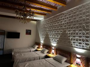 Habitación con 4 camas y lámpara de araña. en DOLON hotel, en Bukhara