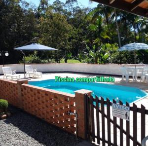 a swimming pool with a fence and chairs and an umbrella at Casa Wunder Platz in Pomerode