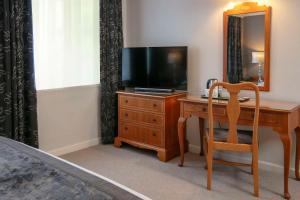 um quarto com uma secretária, uma televisão e uma cadeira em BEST WESTERN Sysonby Knoll em Melton Mowbray