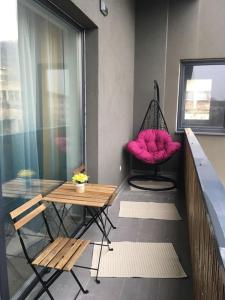 uma varanda com uma cadeira rosa e um baloiço em Dbo-Vivo Mall Apartment em Baia Mare